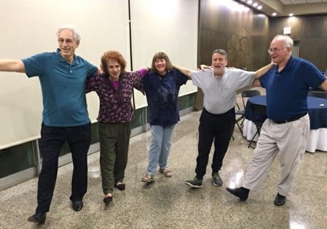 This is a photo that shows several people linking arms in traditional Israeli Dance