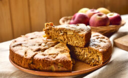 Slice of homemade apple cake Charlotte or american sponge apple pie with walnuts and ripe red apples on the table with linen tablecloth. Healthy seasonal eating.